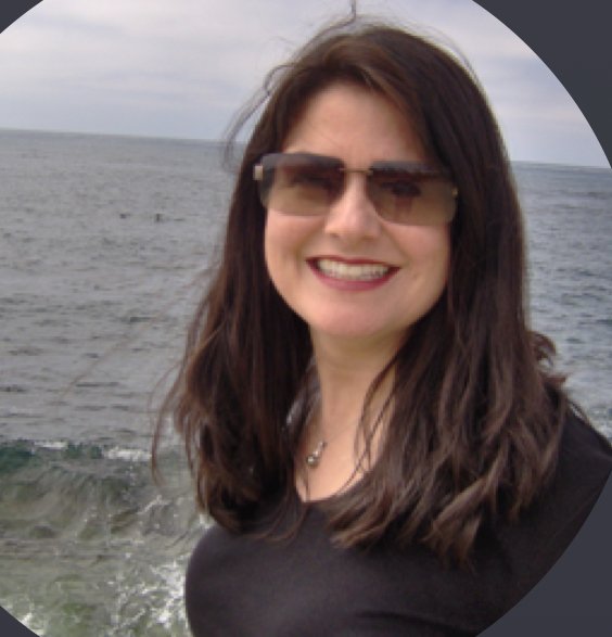 Katie Rose smiling in sunglasses by the ocean